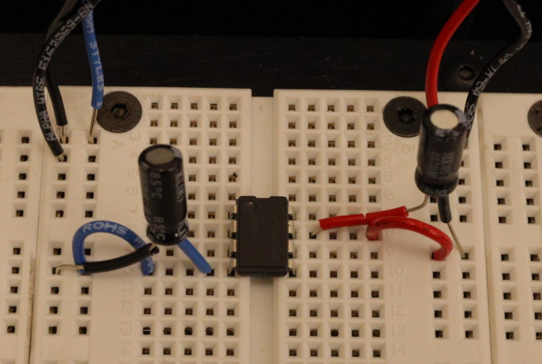The LF356 op-amp DIP chip powered with plus (red) and minus (blue) voltages with decoupling capacitors. Also notice the wire jumping ground to both sides of the chip.